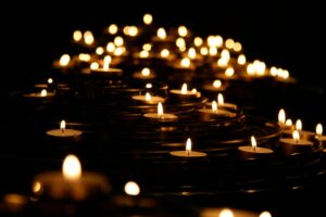 A low-angle photo of tea light candles, lit against the darkness, arranged in tiered glass plates