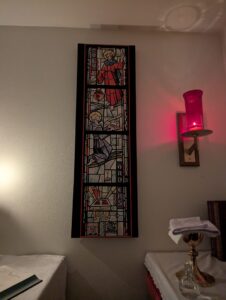 A photo of a canvas reproduction of a stained glass window with the words 'Holy Orders'. Jesus stands at the top of the image above a kneeling man receiving a key.
