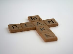 A photo of Scrabble tiles of the words 'make' and 'plan' intersecting at the letter 'a'.