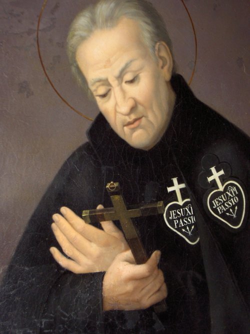 A painting of Saint Paul of the Cross. He looks at a crucifix in his hand and is wearing his habit with the image of a cross and a heart, with the words 'Jesu XPI Passio' ('the Passion of Jesus Christ' in Greek & Latin)