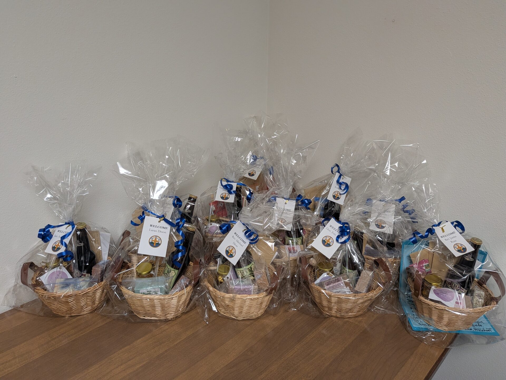 A photo of the gift baskets put together for the staff of the Office of the Vicar for Clergy. Eleven baskets with soda, soap, bath bombs, and thank-you cards - each wrapped, with a nametag on the outside